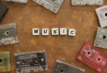 Retro cassette tapes arranged with Scrabble tiles spelling 'Music' on a brown background.