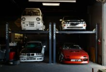 A collection of modified sports cars on a mechanical garage lift in Compton, CA.