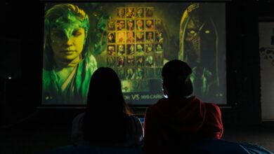 Two people sitting indoors gaming on a large projector screen, enjoying a video game session.