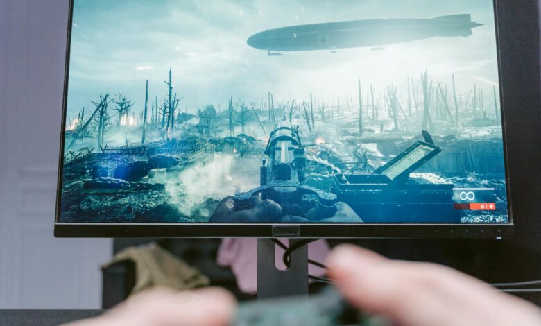 A person playing a video game on a high-resolution monitor, showcasing a war-themed landscape.