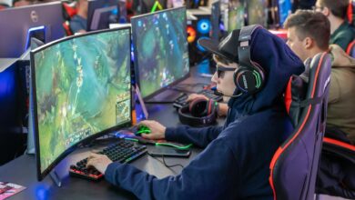 Gamers in an esports tournament playing on high-end gaming setups with monitors, keyboards, and headphones.