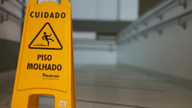 Yellow caution wet floor sign with Portuguese text in an indoor hallway.