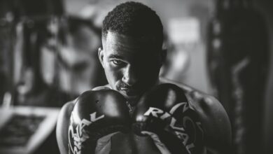 Dramatic black and white portrait of a focused boxer in a gym setting, highlighting strength and determination.