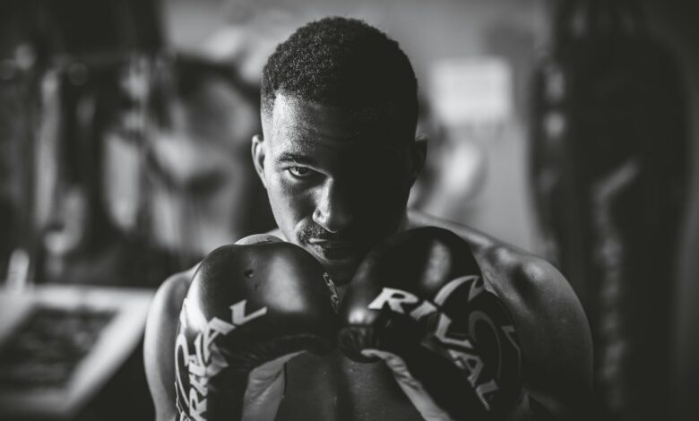 Dramatic black and white portrait of a focused boxer in a gym setting, highlighting strength and determination.