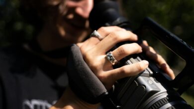 Detailed close-up of a videographer's hands operating a professional video camera.