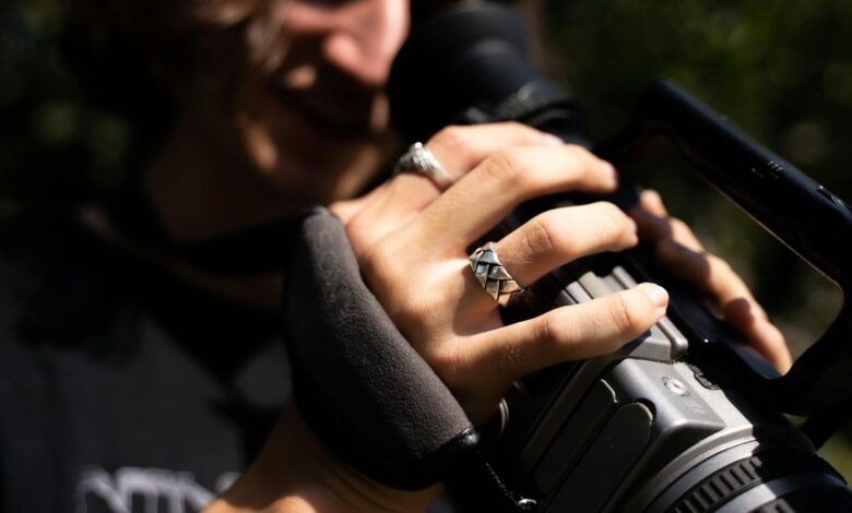 Detailed close-up of a videographer's hands operating a professional video camera.