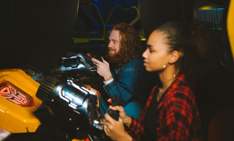 A couple immersed in playing arcade games together, showcasing fun and leisure in a vibrant setting.