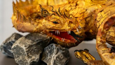 Intricate golden dragon sculpture with detailed scales, set on a rocky base, showcasing artistic craftsmanship.