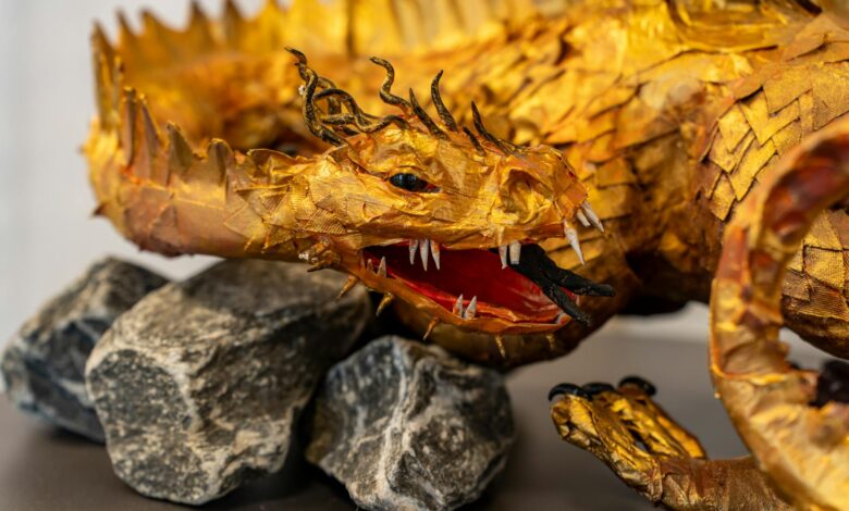 Intricate golden dragon sculpture with detailed scales, set on a rocky base, showcasing artistic craftsmanship.
