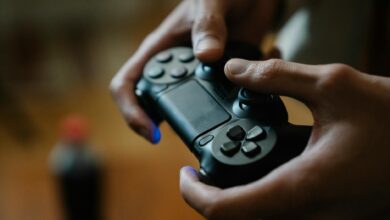 Crop anonymous male pressing buttons on console controller while playing video game in house on blurred background