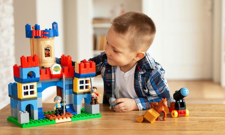 Young boy playing creatively with toy castle and figurines indoors, fostering imagination.