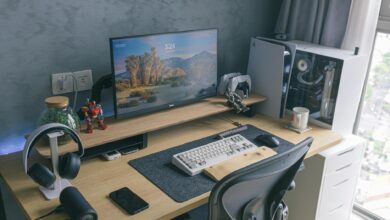 A sleek home office featuring a gaming console, monitor, keyboard, and desk accessories, ideal for technology enthusiasts.