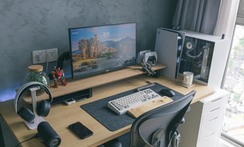 A sleek home office featuring a gaming console, monitor, keyboard, and desk accessories, ideal for technology enthusiasts.