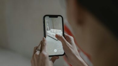 Person using augmented reality on smartphone to visualize a sofa in a room.