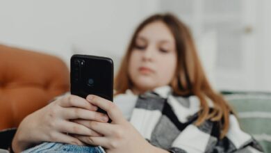 Teenage girl using smartphone while relaxing on a sofa, depicting leisure and connectivity.