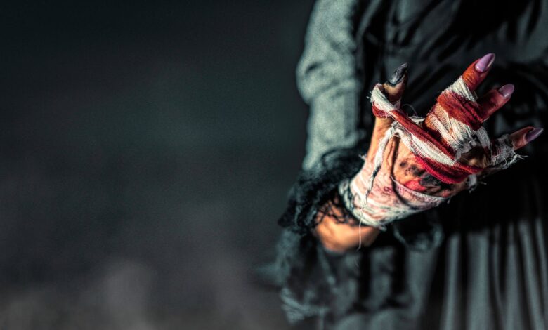 Surreal image of a woman's bloodied, bandaged hand in dark ambiance.