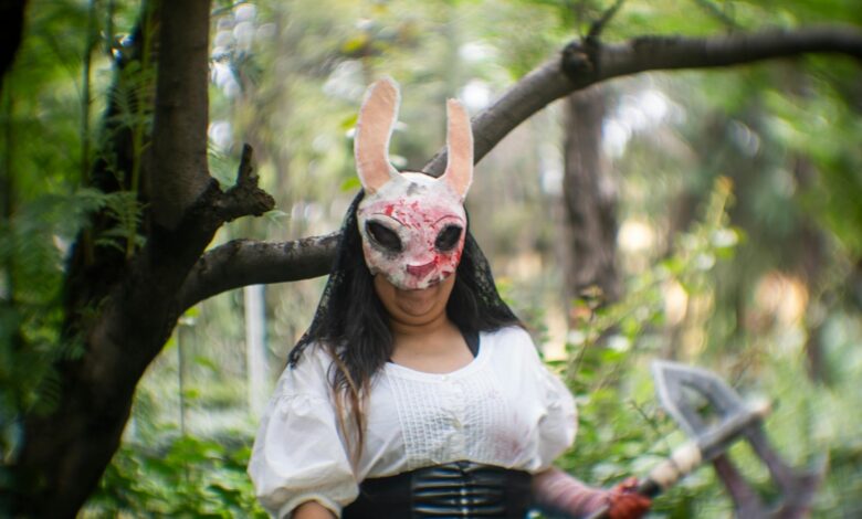 Cosplayer in a forest wearing a distinctive mask, conveying a mysterious theme.