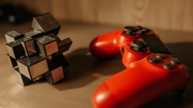 Close-up of a red game controller and 3D cube puzzle on a wooden surface.