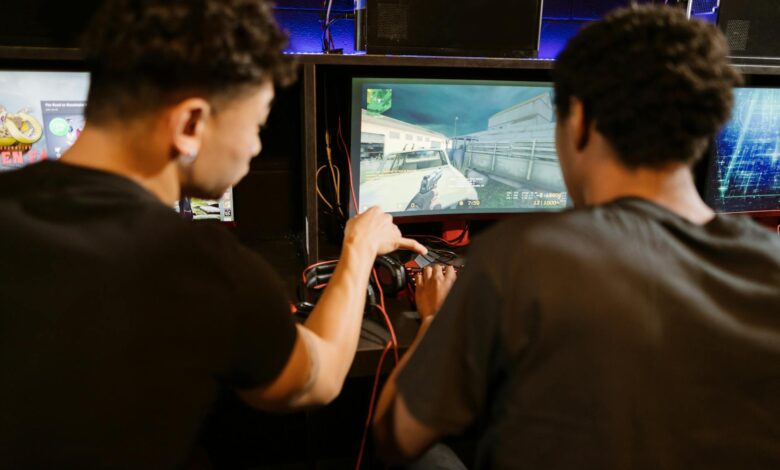 Two young men playing a multiplayer computer game at an arcade with enthusiasm and focus.