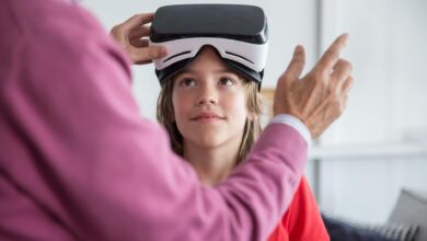 A young girl trying virtual reality goggles for the first time indoors with guidance.