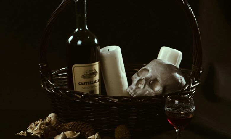 A dark-themed still life featuring a wine bottle, skull, candles, and a basket.