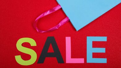 Vibrant shopping sale design with colorful letters and blue bag against a red backdrop.