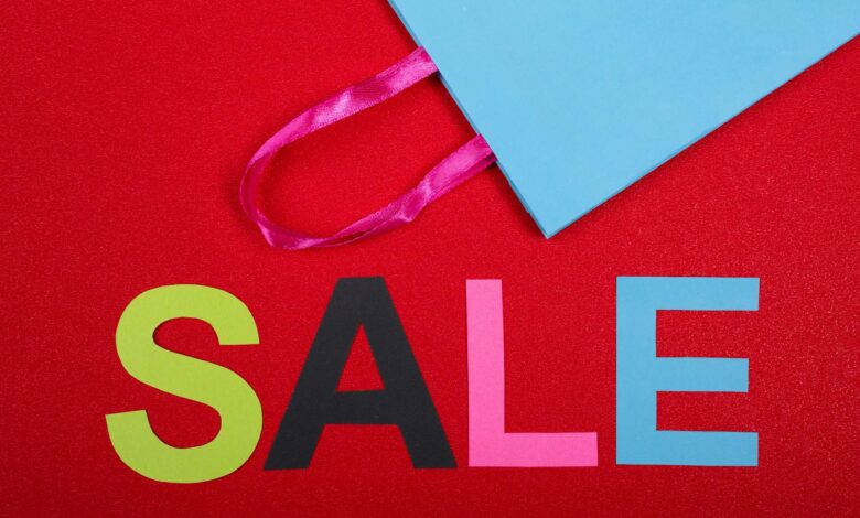 Vibrant shopping sale design with colorful letters and blue bag against a red backdrop.