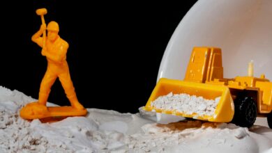 Close-up of toy worker and bulldozer in a conceptual construction scene with kinetic sand.