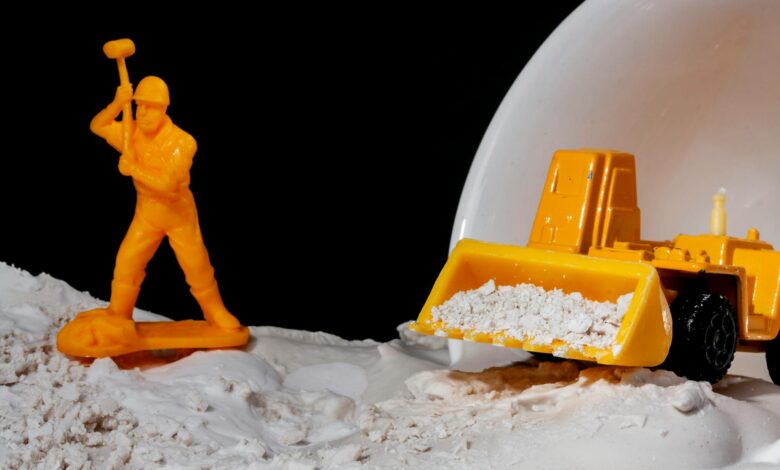 Close-up of toy worker and bulldozer in a conceptual construction scene with kinetic sand.