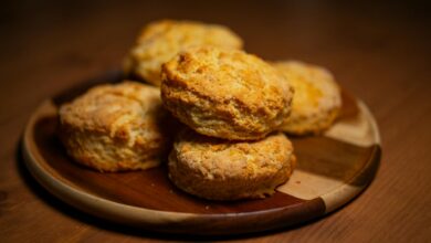 Freshly baked golden biscuits stacked on a wooden plate, perfect for breakfast or tea time.