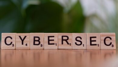 Wooden tiles spell 'CYBERSEC' against a soft-focused green background.