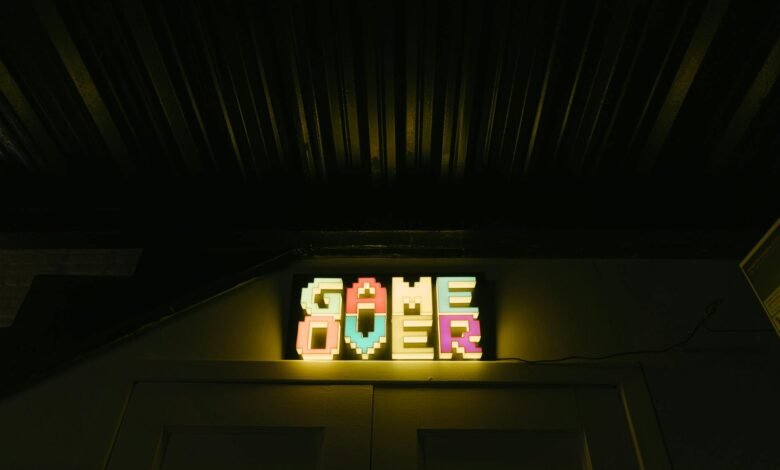 Glowing neon sign with pixelated Game Over text in a dark arcade setting.