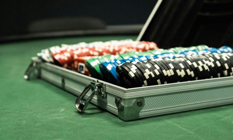Close-up of a poker set with colorful chips arranged in a briefcase on a green table.