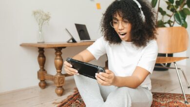 Woman enjoying video game on handheld console indoors, casual setting.