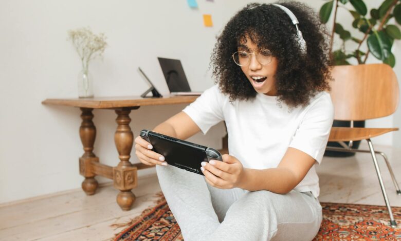 Woman enjoying video game on handheld console indoors, casual setting.