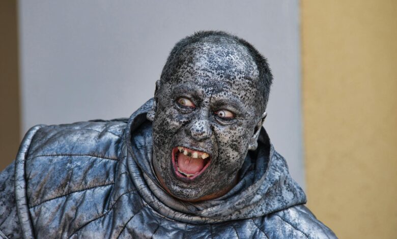 A person wearing a detailed stone statue costume with a scary expression in Kroměříž.