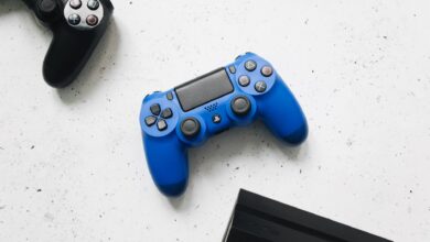 A close-up view of black and blue game controllers on a white speckled surface.