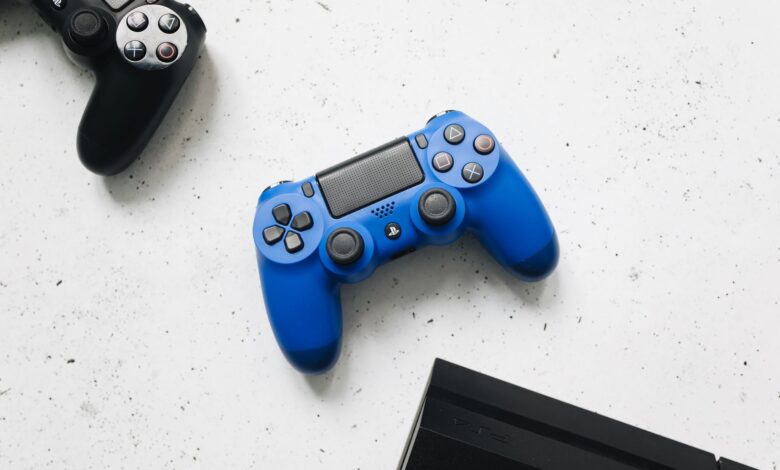 A close-up view of black and blue game controllers on a white speckled surface.