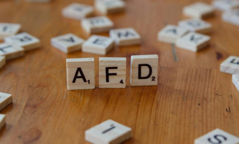 Close-up of scrabble tiles spelling 'AFD' on a wooden table surface, symbolizing political concepts.
