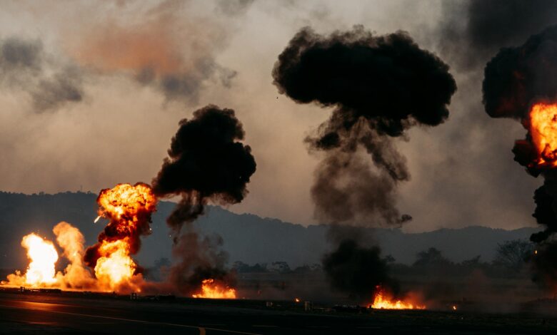 Dramatic scene with explosions and thick black smoke rising in an outdoor setting.