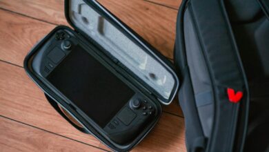 A close-up shot of a gaming console in its case next to a backpack on a wooden floor.