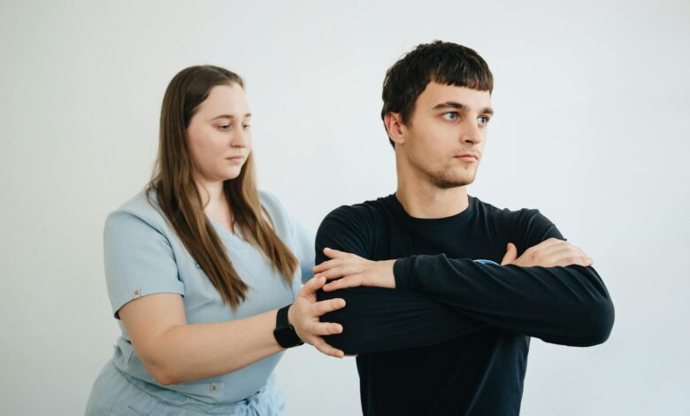 A physiotherapist assists a patient with arm exercises in a clinical setting.