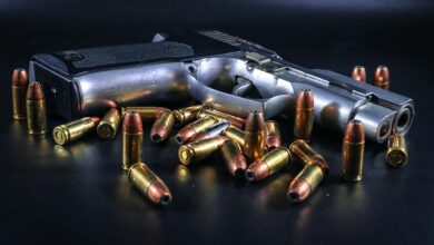 A pistol surrounded by brass bullets on a black background, ideal for weaponry-themed projects.