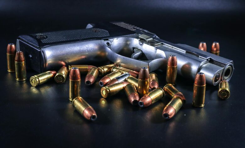 A pistol surrounded by brass bullets on a black background, ideal for weaponry-themed projects.