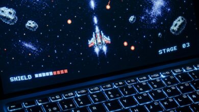 A classic arcade space shooter game displayed on a laptop with illuminated keyboard, showing retro graphics.