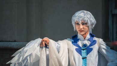 Stunning cosplay portrait with elaborate white and blue costume, showcasing expressive pose and detailed design.