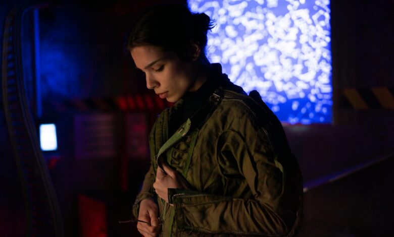 A woman in a sci-fi environment wearing a futuristic jacket, surrounded by technology and lights.