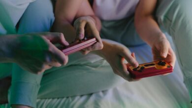 Close-up of a couple's hands holding retro game controllers while gaming indoors.