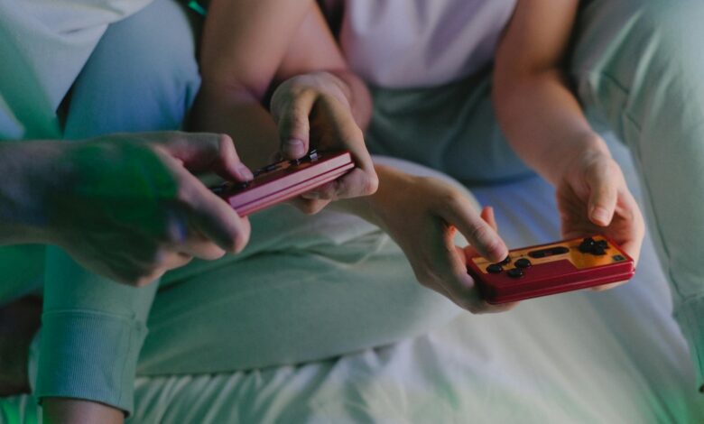 Close-up of a couple's hands holding retro game controllers while gaming indoors.
