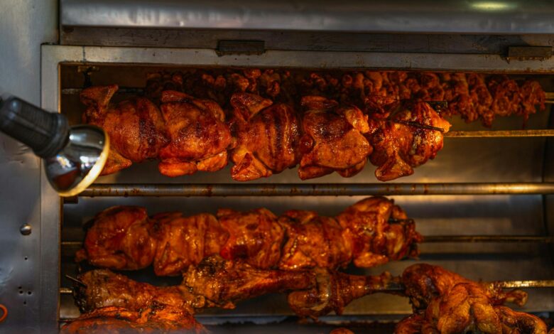 Mouth-watering rotisserie chickens cooking at a street food stall in Ciudad de México, perfect for cuisine lovers.